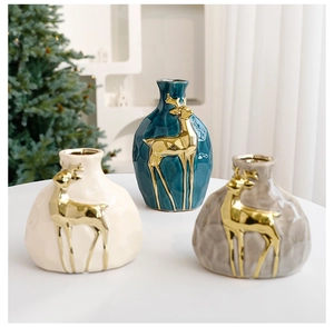 Close-up of geometric ceramic vases with gold reindeer accents for Christmas decor