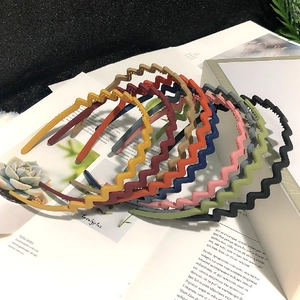 Close-up of colorful wave-shaped headbands stacked on an open magazine with green leaves