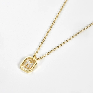 Macro shot of gold-plated S925 silver oval pendant with crystal-encrusted letter M