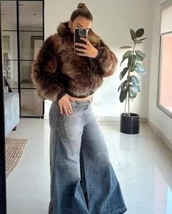 Dettaglio di una giacca in ecopelliccia marrone e jeans grigi a gamba larga in un selfie