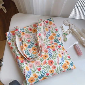Détail du sac cabas en toile à fleurs avec motifs aquarelle et étiquette en tissu blanc