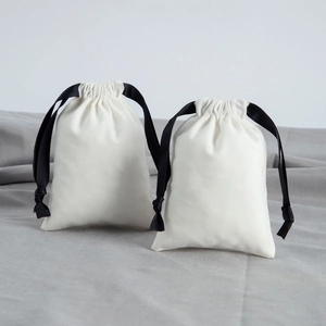Detail of small cotton jewelry pouches with black ribbon drawstring on grey fabric