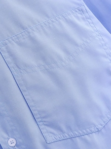 Macro shot of light blue shirt pocket showing precise double-stitch craftsmanship