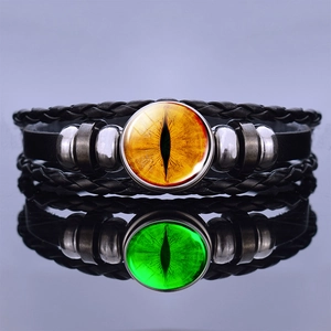 Close-up of steampunk leather bracelets with glowing dragon eye glass charms and reflections