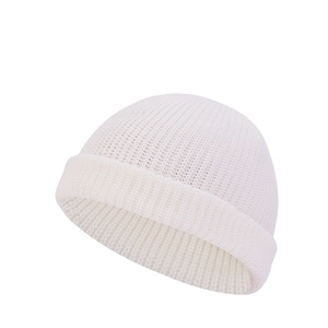 Detail of white knit beanie showing vertical ribbed texture and wide folded brim cuff