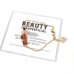 Detail of gold chain bracelet featuring irregular raw carnelian stones and heart charm