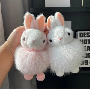 Close-up of soft plush bunny keychains in pink and white with fluffy fox fur texture