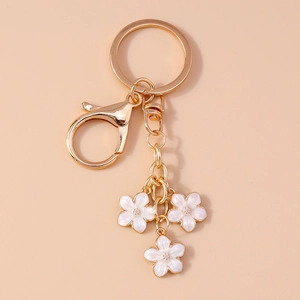 Detailed close-up of sweet white sakura flower pendants on a golden metal keychain