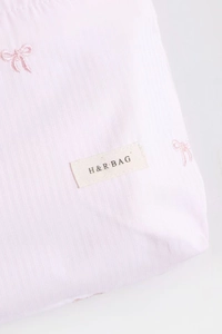 Gros plan sur la texture du tissu rayé rose avec broderie de nœuds et étiquette tissée