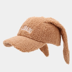 Detail of fluffy brown sherpa baseball cap with rabbit ears and white embroidery