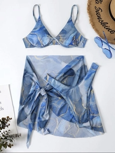 Detailed flat lay of blue marble print three-piece bikini set with sheer sarong and straw hat