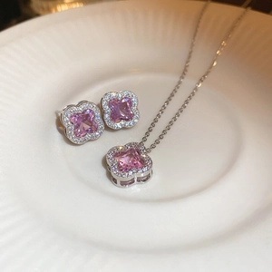 Close-up of pink zircon flower necklace and earrings set on a white ceramic plate