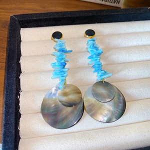 Close-up of bamboo-style round shell earrings with blue stone beads and black studs