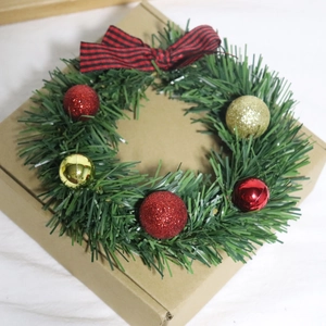 Detail of Christmas wreath with red gold balls and striped bow on green pine needles