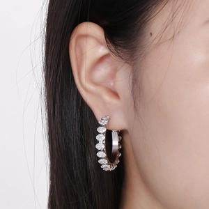 Macro detail of silver circle earrings with inlaid white zircon stones on model ear
