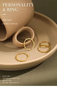 Detailed view of four minimalist gold textured rings placed on a ceramic dish