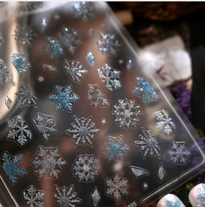 Macro view of holographic snowflake nail art stickers with glitter finish on dark backdrop