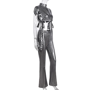 Vista laterale del crop top argento metallizzato con ritaglio e pantaloni svasati a vita alta