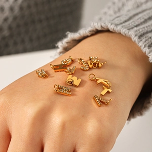 Pendentif alphabet doré en acier inoxydable avec diamants présenté sur la main