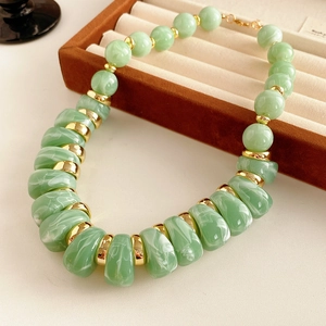 Détail du collier vintage avec perles en pierre verte et accents dorés élégants