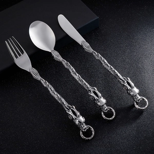 Detail of silver stainless steel cutlery set with embossed dragon handle design