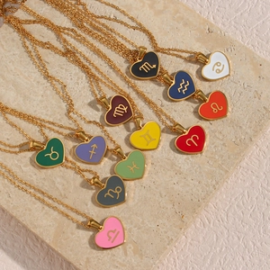 Golden heart zodiac necklaces with colorful enamel pendants on a stone surface