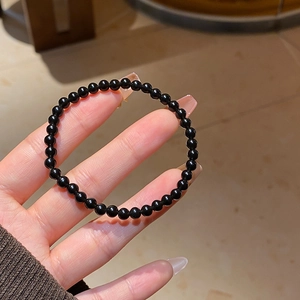 Macro detail of glossy black obsidian beads showing the smooth reflective surface of the bracelet