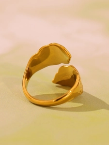 Macro shot of gold leaf-shaped open ring featuring textured matte and polished finish
