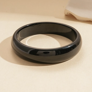 Detailed view of polished black resin round bangle with a high-gloss mirror finish