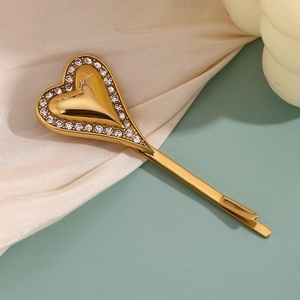 Detailed close-up of 18K gold heart hair clip with diamonds on silk fabric