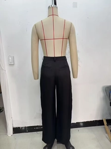 Detail view of high-waisted black satin wide-leg trousers showing back waistband and pockets