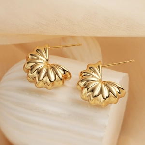Close-up of gold plated irregular geometric earrings on a white textured base
