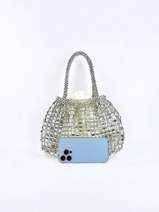 Detailed shot of a silver metal woven handbag with a satin inner pouch and a phone for scale