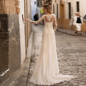 Long sleeve lace wedding dress with deep V-neck, open back, and small train detail