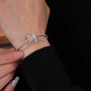 Detail of silver double-layered butterfly and flower cuff bracelet worn on hand