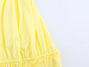 Close-up of yellow halter top featuring elastic pleated hem and soft fabric texture