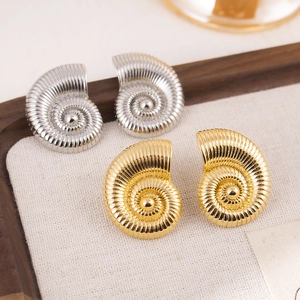 Chic silver and gold nautilus shell stud earrings with spiral texture on beige fabric