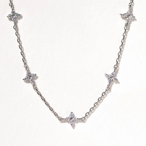 Silver flower necklace with sparkling zircon clover charms on a white background