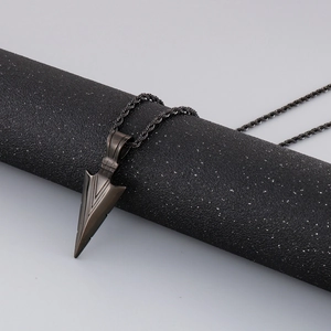 Detail of black stainless steel arrow pendant hanging on a modern minimalist display stand