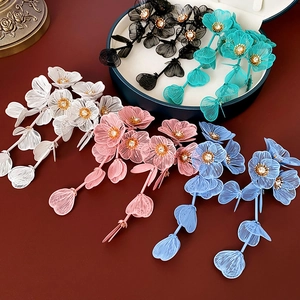 Détail de boucles d'oreilles à pompons fleuris avec pétales en maille et strass brillants