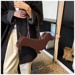 Detail of dachshund-shaped handbag in dark brown faux leather held by a model