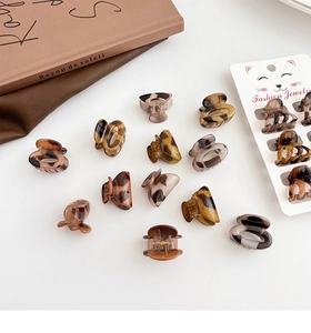 Detailed view of leopard print mini hair claws set on a white background with decorative book