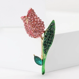 Close-up of golden tulip brooch with pink and green rhinestones on white steps