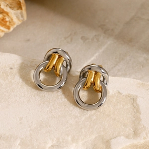Boucles d'oreilles nœud minimalistes bicolores or et argent sur un support en pierre
