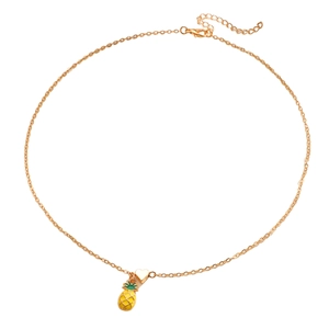 Dettaglio di una collana dorata con ciondolo a forma di ananas giallo e cuore su sfondo bianco