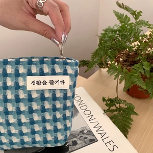 Détail de la trousse tissée à carreaux bleu et blanc avec fermeture éclair métallique