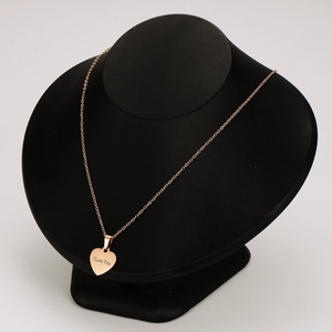Collier cœur en or rose avec gravure I Love You sur un support de bijoux noir