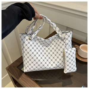 Nahaufnahme der weißen Tote Bag und passender Tasche mit schwarzem Kettenmuster auf Holztisch
