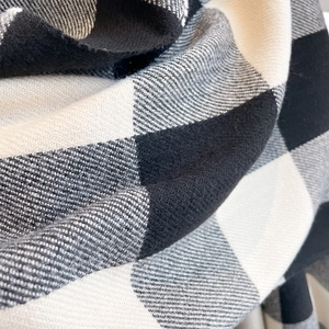 Close-up of soft plaid cashmere-like fabric showing grey and black check weave texture