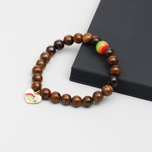 Detail of tiger eye bead bracelet with heart rainbow charm on a black gift box edge